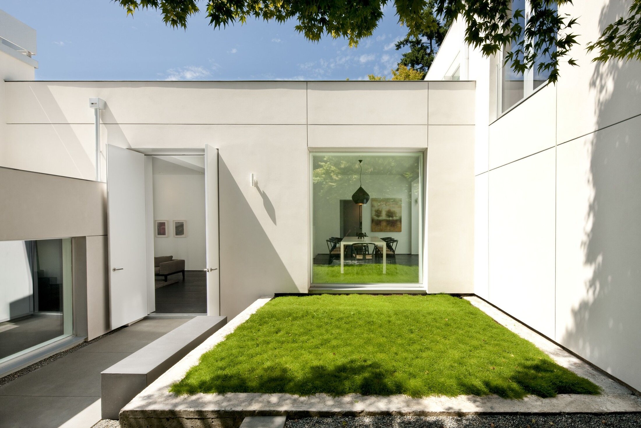 Minimalist White Facade with Integrated Green Patio