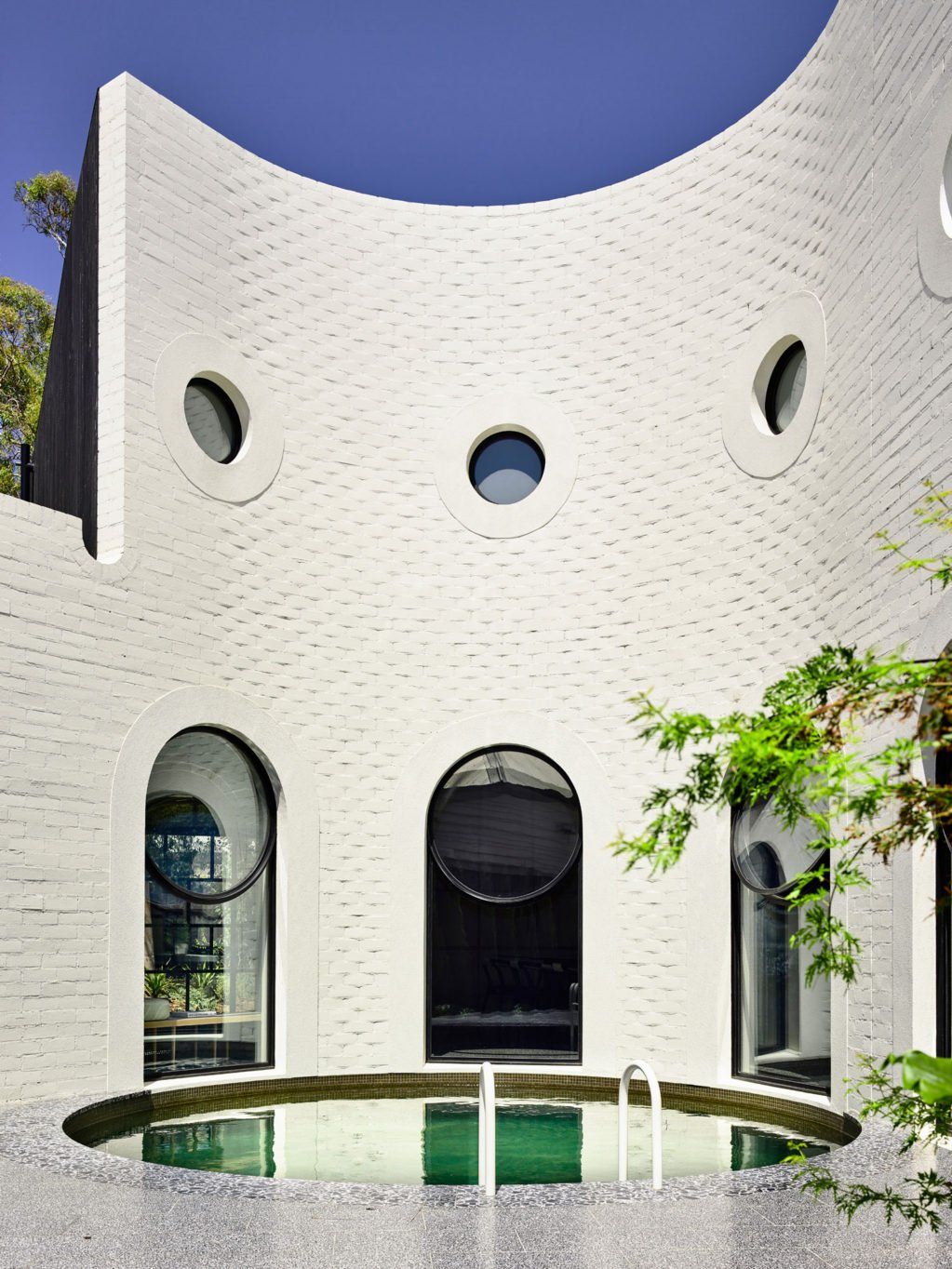 White textured facade with round windows and curved shape