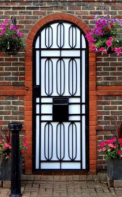 Arched Metal Door in Brick Facade: Geometry and Floral Framing