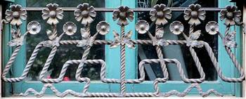 Decorative wrought iron grille with floral ornament on turquoise facade