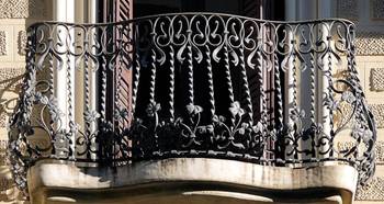 Elegant Art Nouveau wrought iron balcony railing on a textured facade