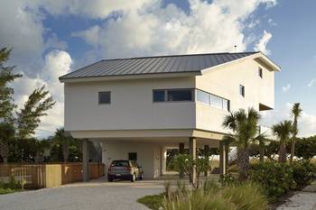 Coastal Minimalism: Light Facade on Stilts with Metal Roofing