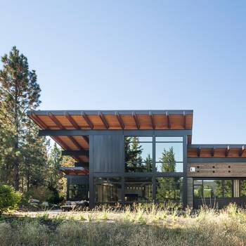 Contemporary mountain house facade with cantilevered roof: a dialogue of metal, wood and glass