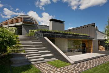 Multi-level house with contrasting facade: concrete, glass, and green roofs