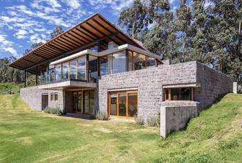 Two-level house with contrasting facade: stone base and glass pavilion