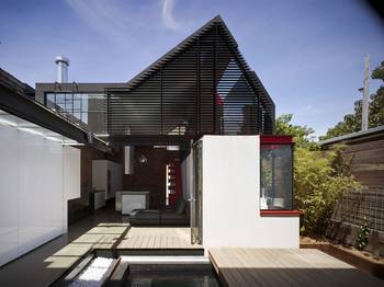 Modern house with contrasting facade: triangular geometry and louvered cladding