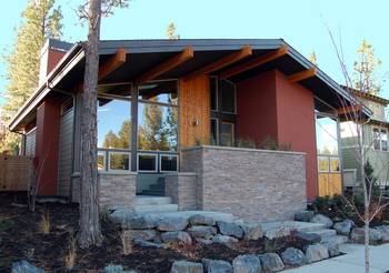 Contemporary mountain facade with warm terracotta finish and natural stone