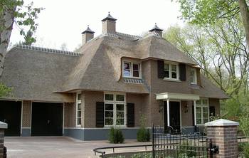 Traditional Dutch house with thatched roof: harmonious facade of brick and reed