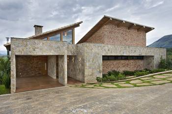 Modern stone and brick facade with asymmetrical roof in mountain landscape