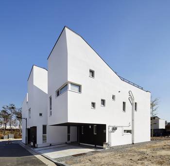 Minimalist white facade with contrasting base: geometry and asymmetry in contemporary architecture