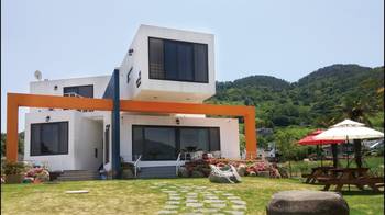 Minimalist Facade with Orange Portal: Contemporary Home Surrounded by Nature