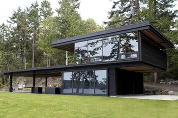 Black minimalist facade with panoramic glazing in forest surroundings