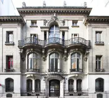 Elegant Classical Facade of a French Mansion with Decorative Ironwork and Expressive Stucco