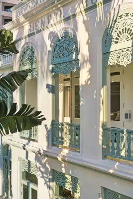 Tropical Colonial Facade: Turquoise Fretwork Details Against White Background