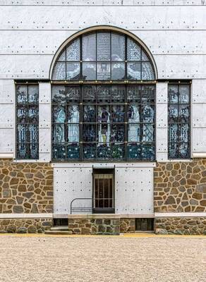 Modernist facade with stained glass semi-circular window and contrasting stone cladding