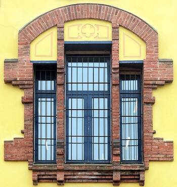 Arched window with brick framing on a yellow facade