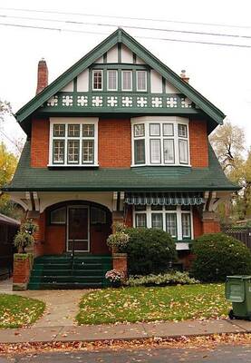 Elegant Tudor Revival House Facade with Contrasting Brick and Green Decorative Elements