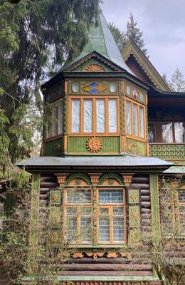 Carved green facade of a Russian dacha with a traditional-style corner turret