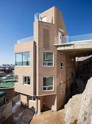 Integrated Brick Facade: Modern Building Embedded in Rock Formation