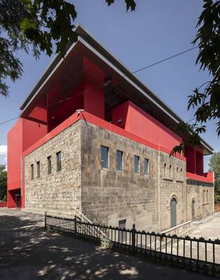 Contrasting Facade: Historical Stone Base with Contemporary Red Superstructure