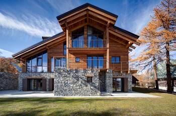 Modern Alpine Chalet: Harmonious Stone and Wood Facade with Panoramic Glazing