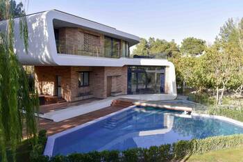 Modern two-story house with contrasting facade: brick foundation and streamlined white top