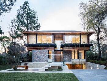 Modern two-story house with a combined façade of stone, wood, and glass