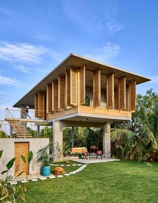 Tropical house with wooden louvered facade on concrete pillars