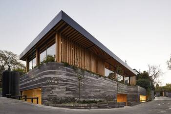 Modern house with contrasting facade: stone foundation and wooden slats