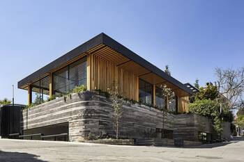 Modern facade with textural contrast: stone base and wooden slats