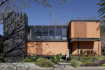 House with Contrasting Facade: Combination of Dark Panels and Perforated Brickwork