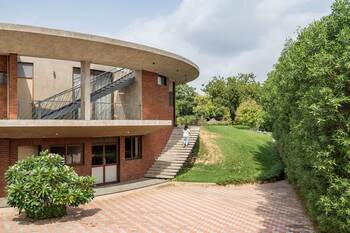 Modern house with curved concrete facade and brick base on a slope