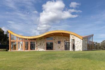 Wave-shaped facade of a country house with natural stone and panoramic glazing