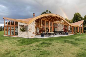 Undulating Facade: Harmony of Stone and Wood Under a Curved Roof