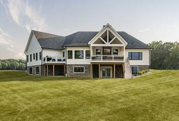 Elegant country house with a two-level facade: combination of stone and siding