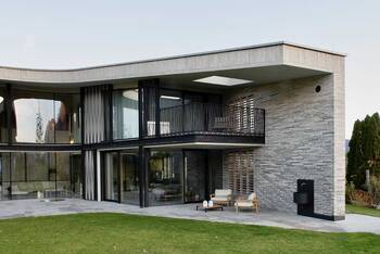 Modern house with undulating roof and textured stone and glass facade