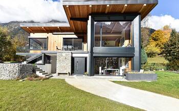 Modern mountain house with contrasting facade of wood, stone and glass