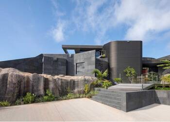 Brutalist façade integrated into rocky landscape: modern house with contrasting textures