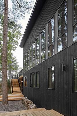 Modern black facade with panoramic glazing in forest surroundings