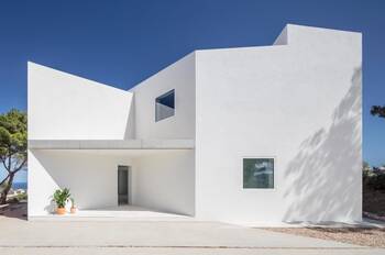 Minimalist white façade with geometric volumes and focal window openings