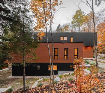 Contrasting facade of a modern house with wooden cladding in autumn forest