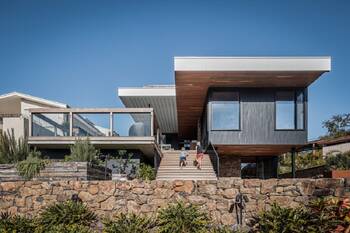 Modern facade with contrasting materials: wood, glass and stone on a stepped terrain