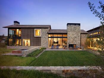 Modern country house with stone and wood facade featuring horizontal louvers