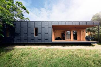 Contemporary minimalist house with contrasting facade of metal panels and wooden terrace