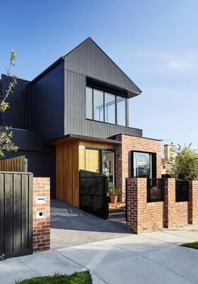 Three-layered facade of a modern house: harmony of metal, wood and brick