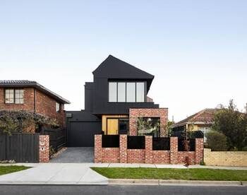 Modern two-level facade with contrasting combination of black upper volume and brick base