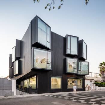 Modular black facade with protruding glass bay windows