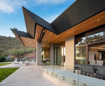 Dynamic desert house facade with contrasting roof overhangs and wooden finishing