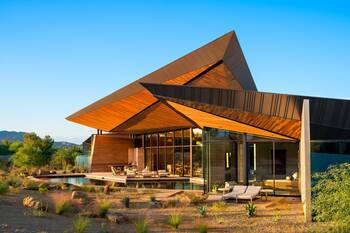 Dynamic wooden facade with angular roof in desert landscape