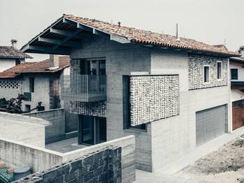 Textured concrete facade with stone inserts and traditional tiled roof